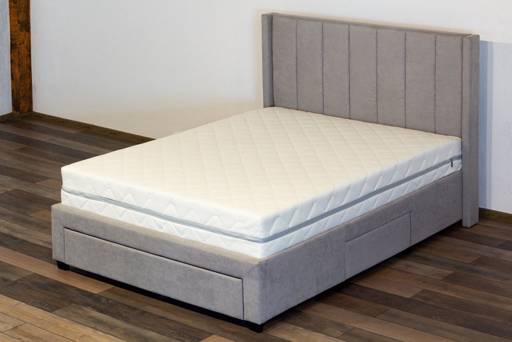 Gray upholstered bed with a white mattress on a wooden floor.