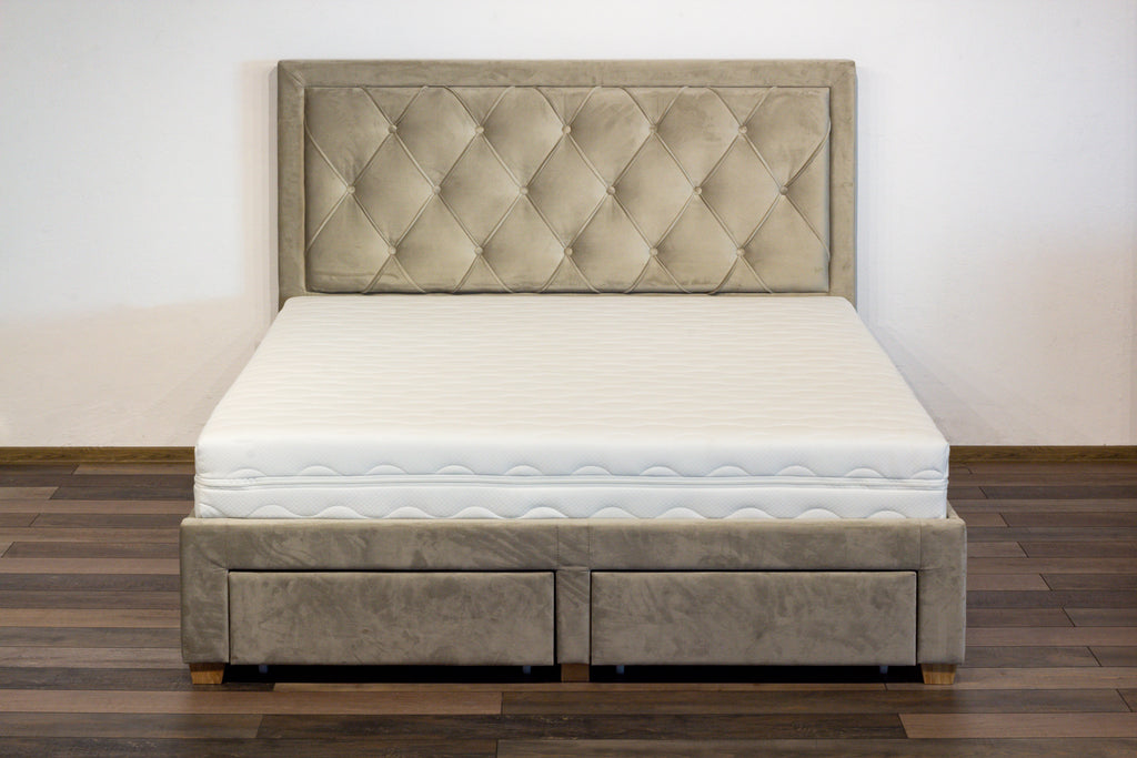 Beige upholstered bed with tufted headboard on a wooden floor.