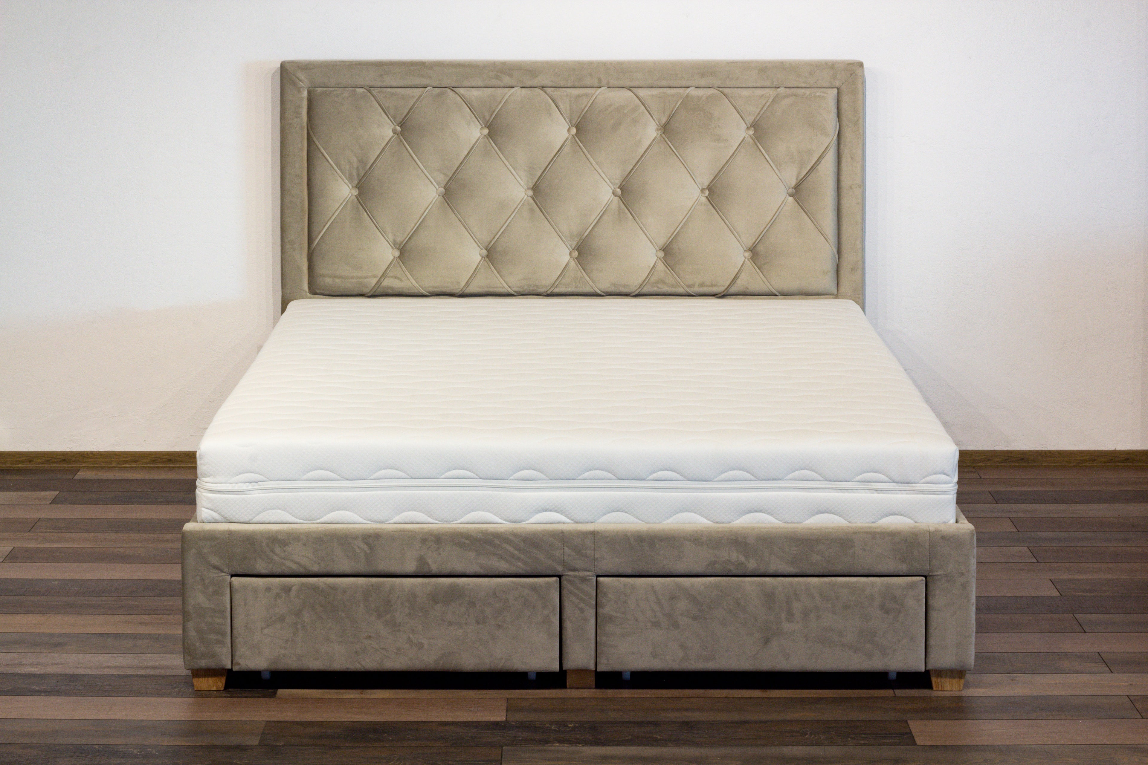 Beige upholstered bed with tufted headboard on a wooden floor.