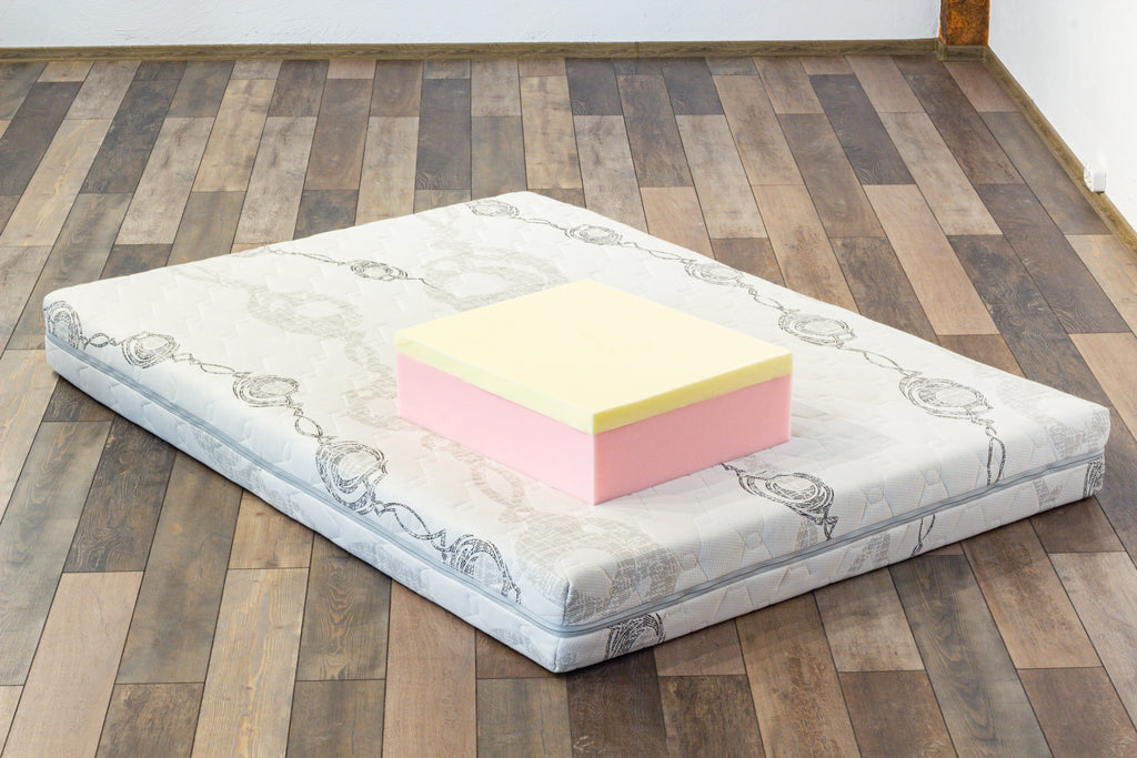 Pink and yellow foam block on a mattress on a wooden floor