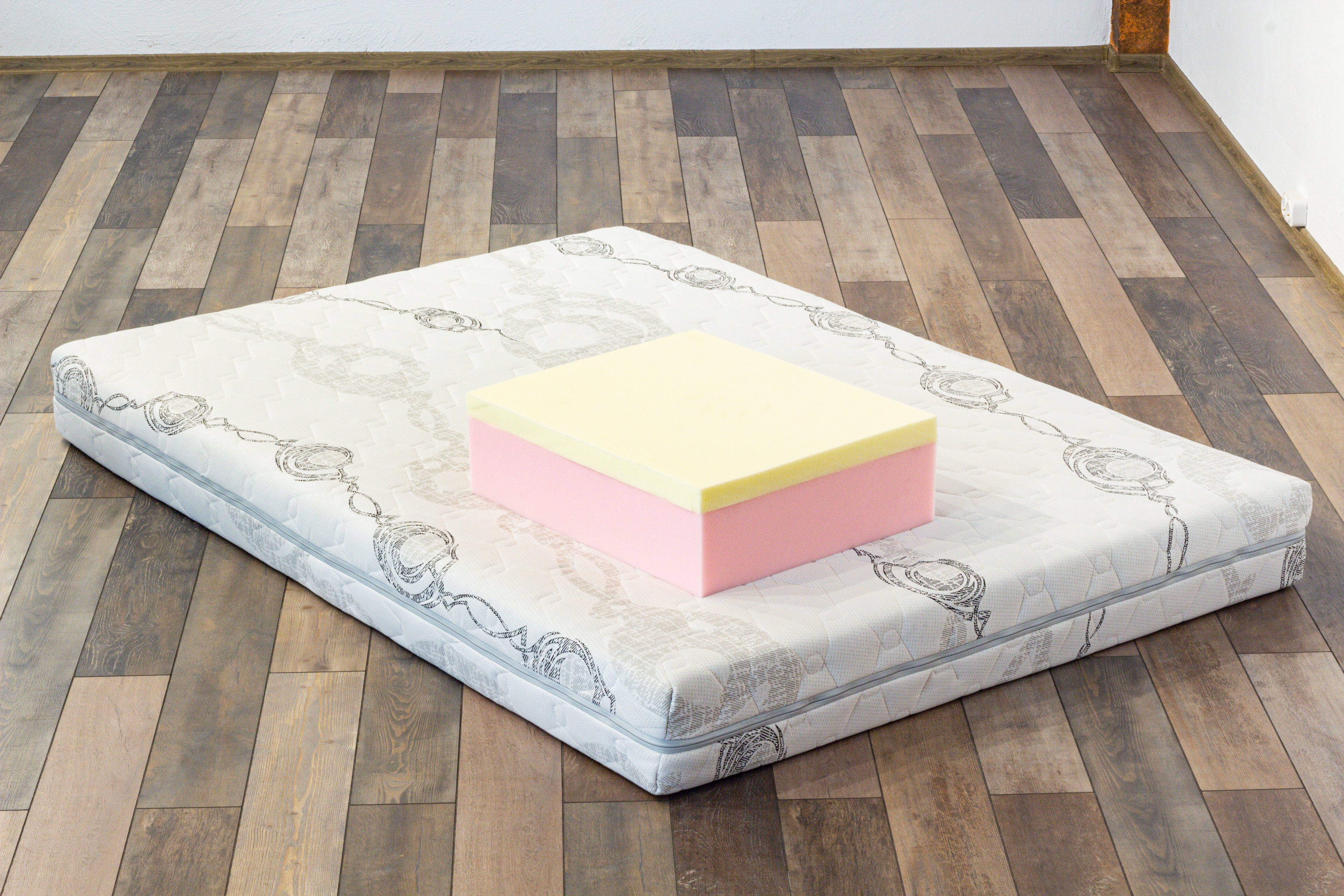 Pink and yellow foam block on a mattress on a wooden floor
