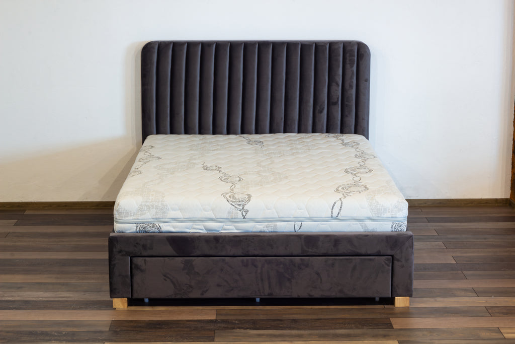 Gray upholstered bed with a mattress on a wooden floor.