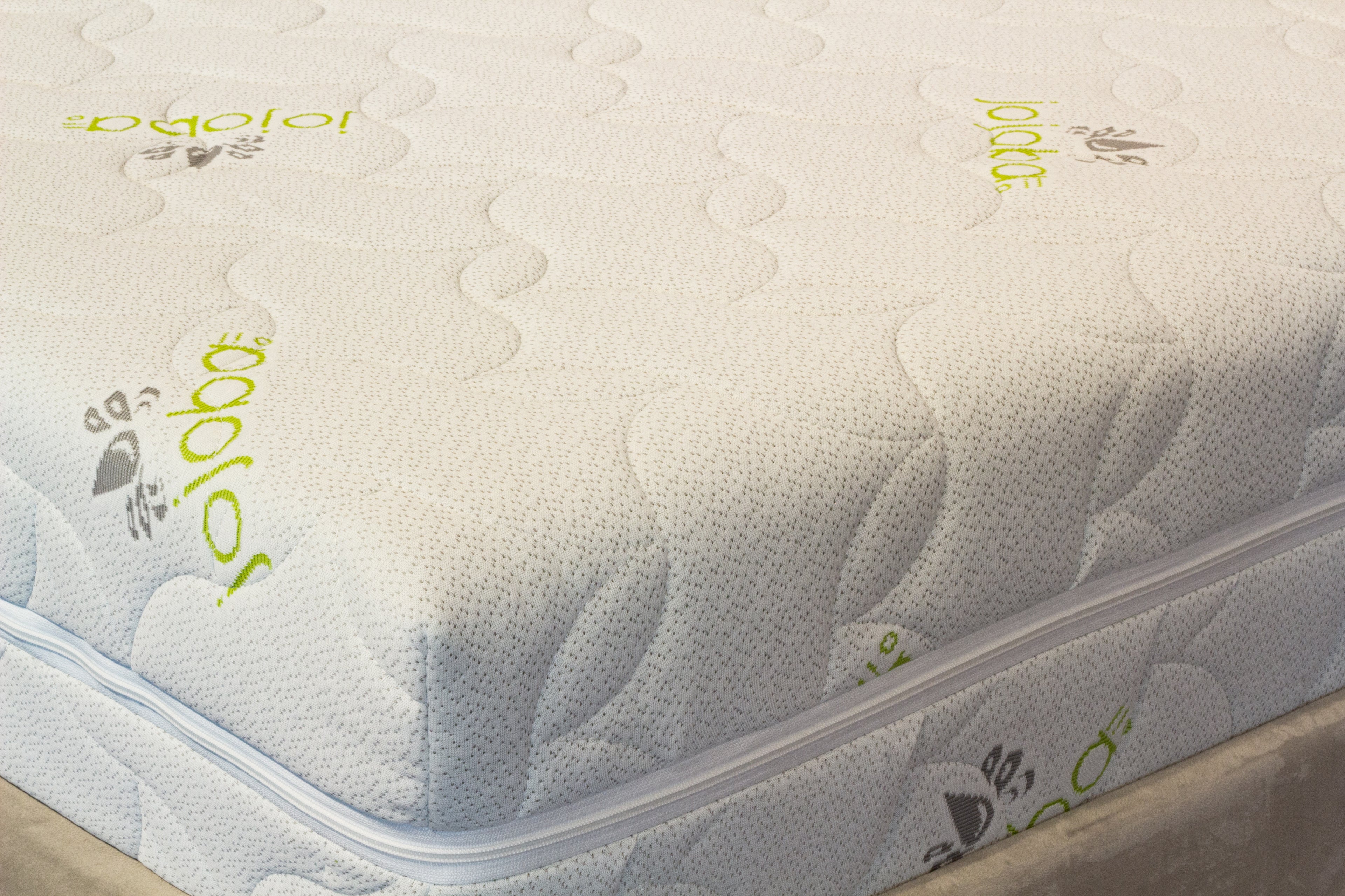 Close-up of a mattress with 'Jojoba' branding on a white background