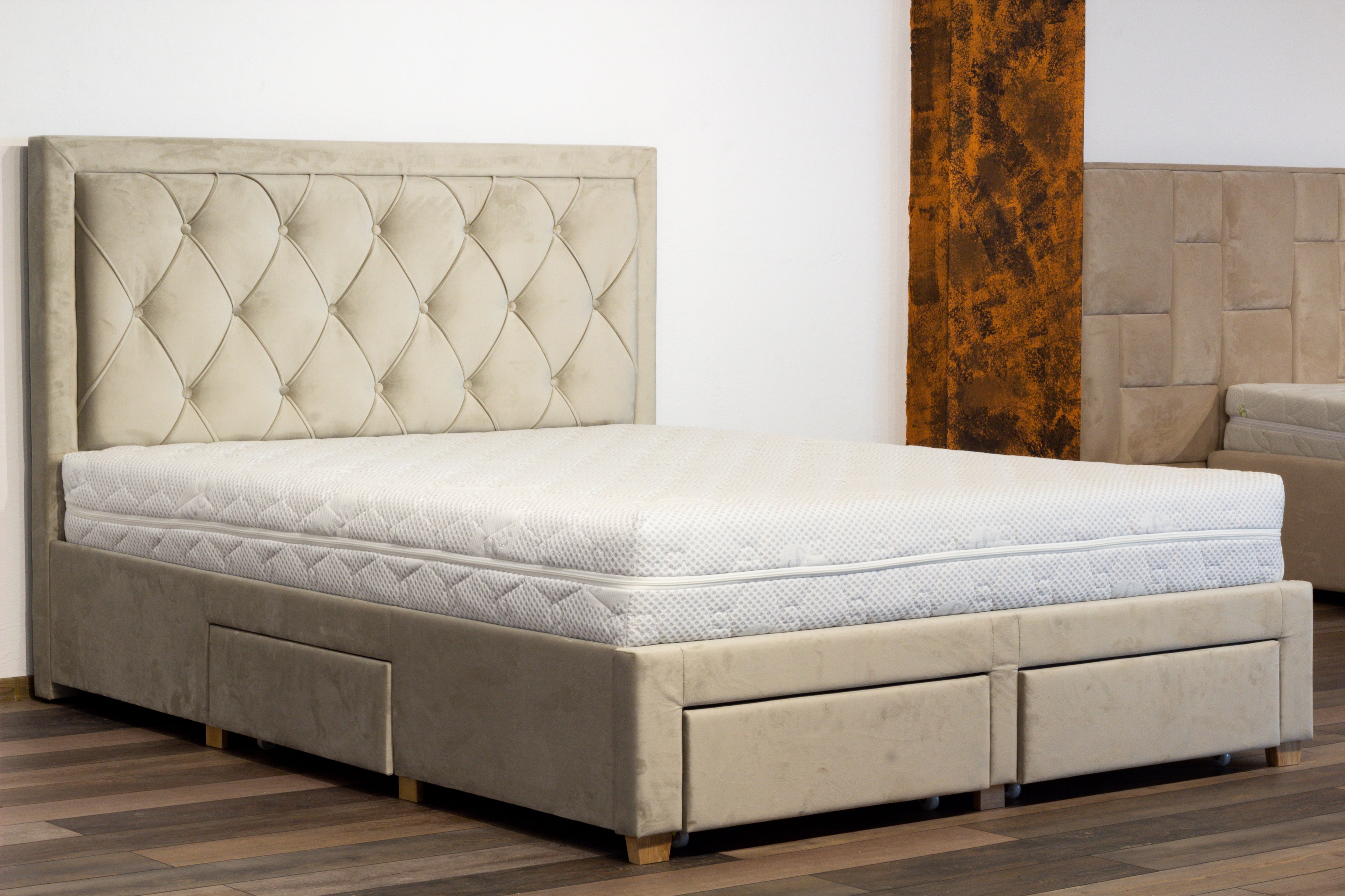 Beige upholstered bed with tufted headboard in a room setting