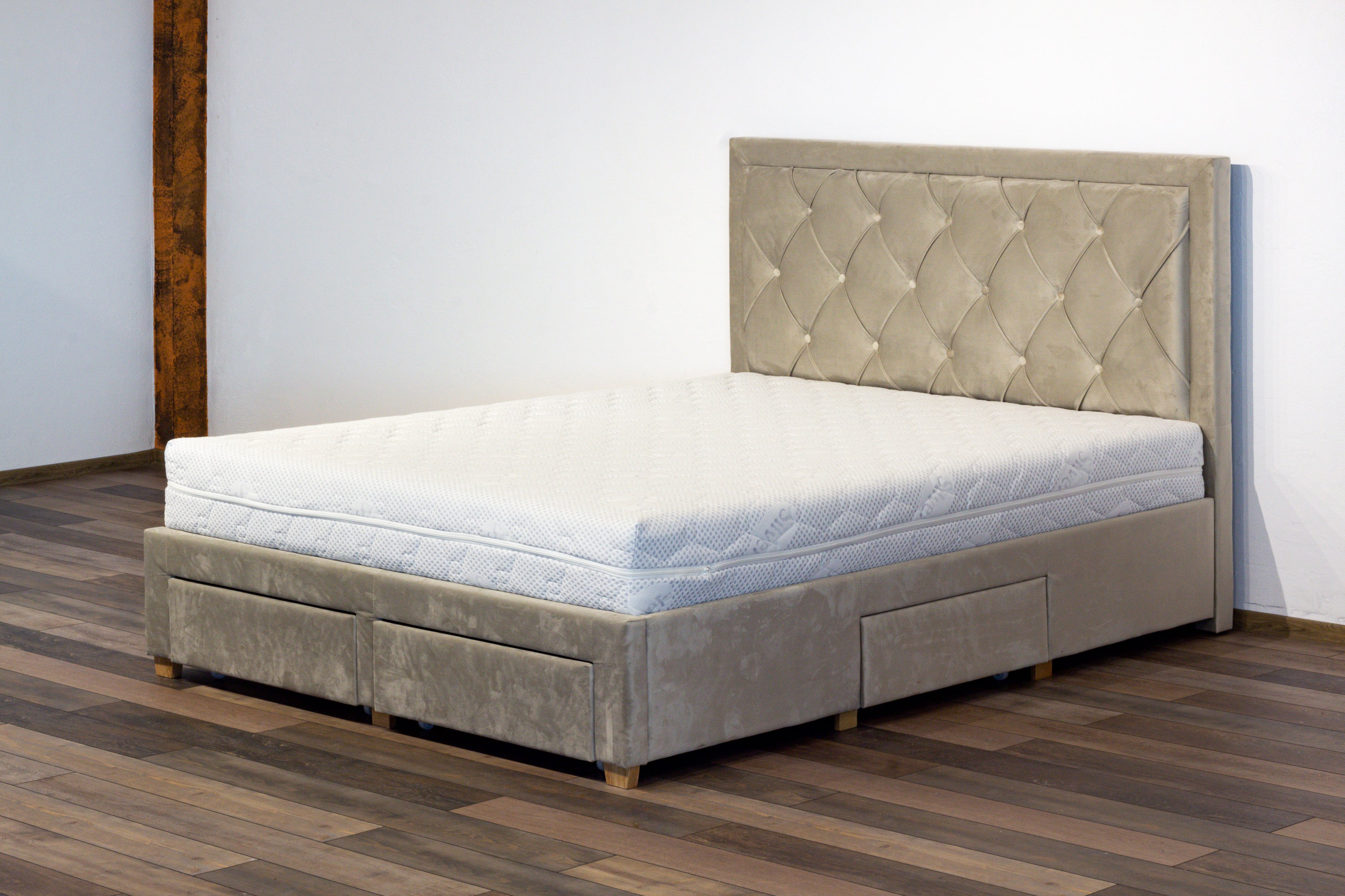 Gray upholstered bed with tufted headboard on a wooden floor.