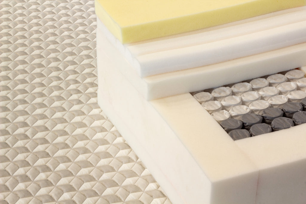 Close-up of various foam layers with different textures and colors on a textured surface.
