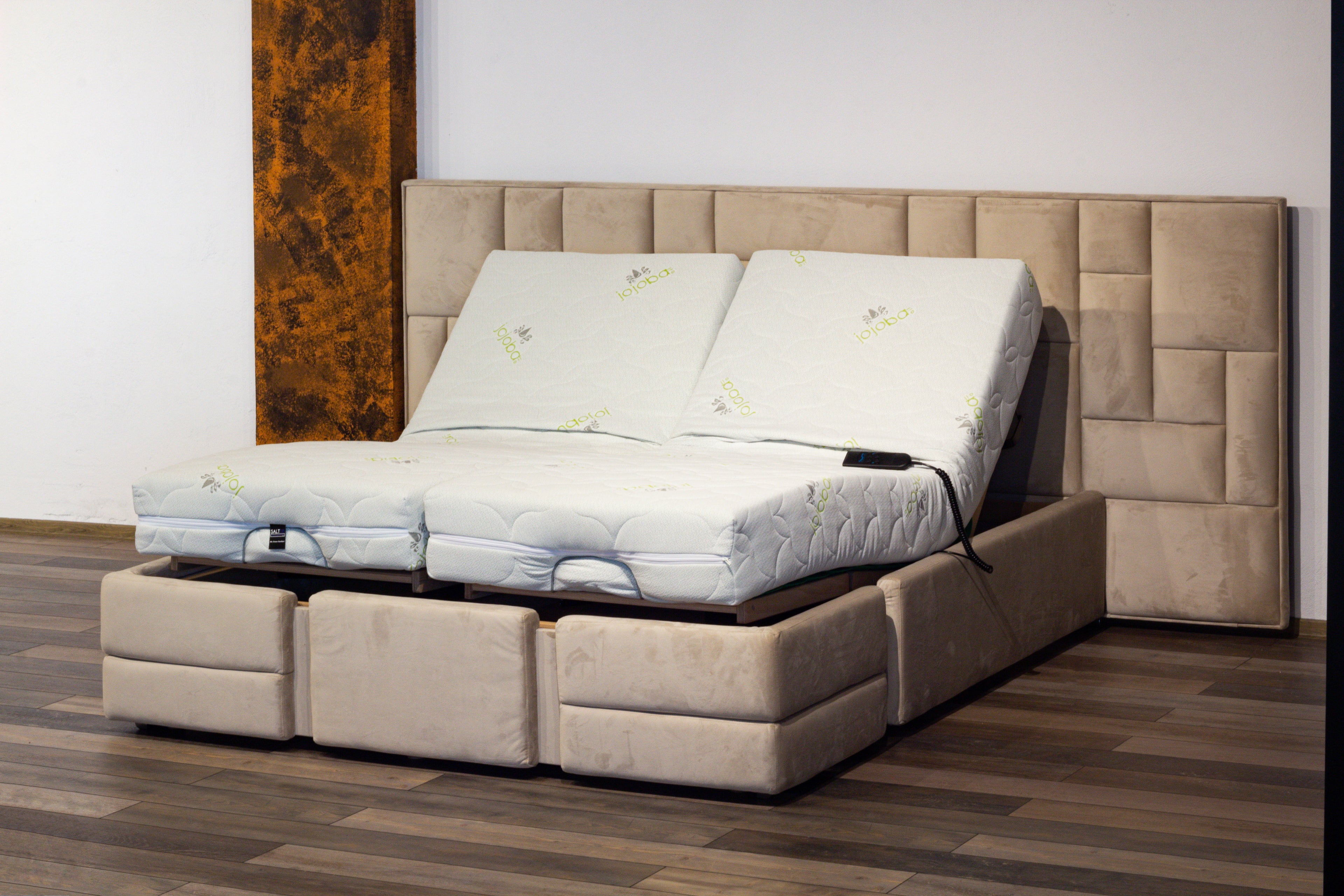 Beige adjustable bed with mattress on a wooden floor.
