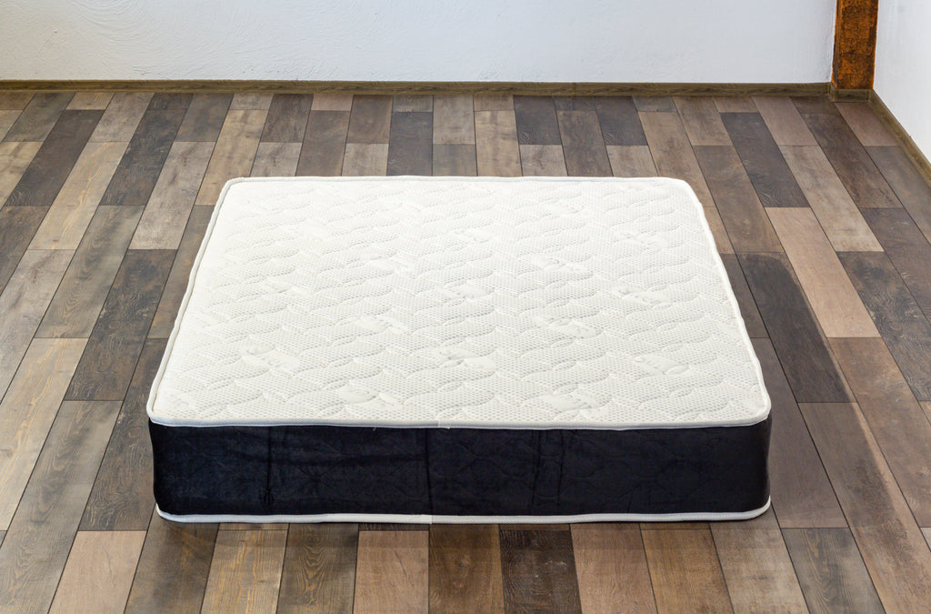 Mattress on a wooden floor with a white wall background