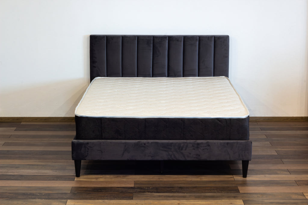 Black bed frame with mattress on a wooden floor