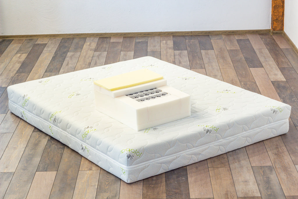 Mattress on a wooden floor with a white wall background