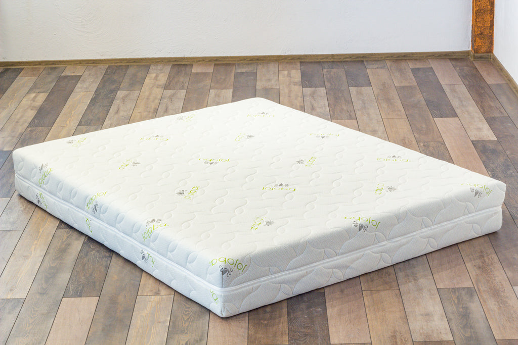 Mattress on a wooden floor with a white wall background