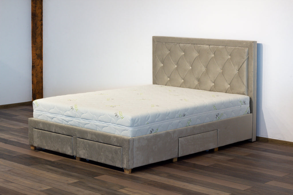 Gray upholstered bed with mattress on a wooden floor